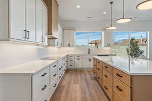 Kitchen with white cabinetry, sink, pendant lighting, and black electric cooktop