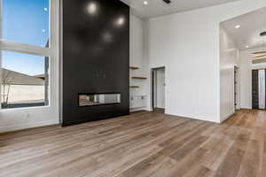 Unfurnished living room with a high ceiling, a fireplace, and light hardwood / wood-style floors