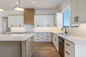 Kitchen featuring dark hardwood / wood-style floors, decorative light fixtures, dishwasher, sink, and white cabinets