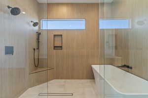 Bathroom featuring shower with separate bathtub, a healthy amount of sunlight, and tile walls