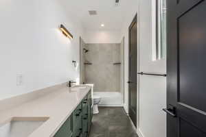 Full bathroom with vanity, tiled shower / bath combo, and toilet