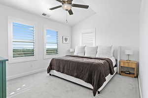 Carpeted bedroom featuring ceiling fan and vaulted ceiling