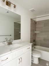 Full bathroom with tile patterned floors, vanity, toilet, and tiled shower / bath combo