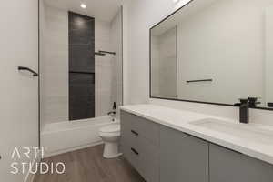 Full bathroom featuring vanity, toilet, tiled shower / bath combo, and hardwood / wood-style floors