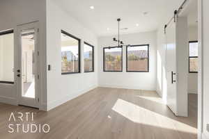 Unfurnished dining area featuring a barn door and light hardwood / wood-style flooring