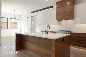 Kitchen featuring white cabinetry, a barn door, pendant lighting, and light hardwood / wood-style flooring