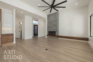 Unfurnished living room with ceiling fan, a stone fireplace, and light hardwood / wood-style floors