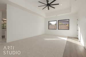 Empty room with ceiling fan and a tray ceiling