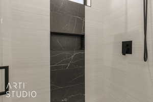 Interior details featuring tiled shower and a premium fireplace