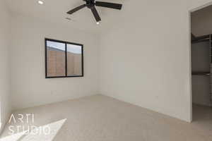 Unfurnished bedroom featuring a walk in closet, light carpet, ceiling fan, and a closet