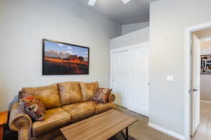 Carpeted living room featuring vaulted ceiling and ceiling fan