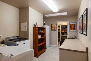 Washroom featuring light wood-type flooring, washer and dryer, and a textured ceiling