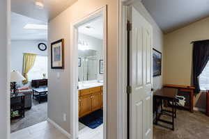 Hall featuring lofted ceiling with skylight, sink, and light carpet