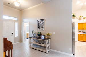 Foyer entrance with vaulted ceiling and light wood-type flooring