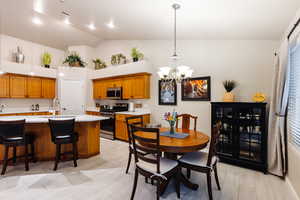 Kitchen featuring sink, appliances with stainless steel finishes, hanging light fixtures, a kitchen breakfast bar, and light hardwood / wood-style floors