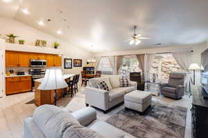 Living room with high vaulted ceiling and ceiling fan with notable chandelier