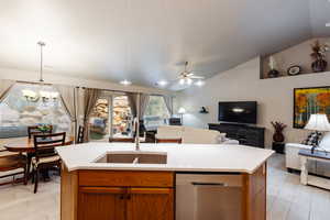 Kitchen with a kitchen island with sink, sink, decorative light fixtures, and stainless steel dishwasher