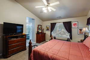 Carpeted bedroom with vaulted ceiling, ceiling fan, and ensuite bath