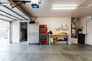 Garage featuring a garage door opener, gas water heater, and a workshop area