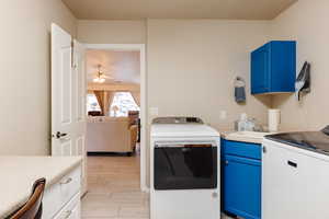 Clothes washing area with washer / clothes dryer, cabinets, sink, and light wood-type flooring