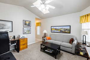 Carpeted living room with ceiling fan and vaulted ceiling