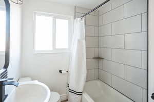 Full bathroom featuring toilet, sink, and shower / bath combo with shower curtain