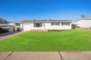 Single story home with a garage and a front lawn