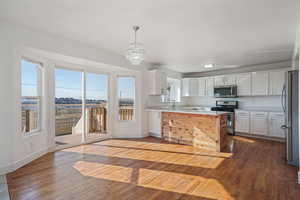 Kitchen featuring pendant lighting, wood-type flooring, stainless steel appliances, and white cabinets