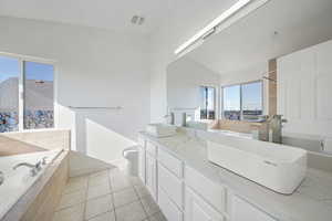 Full bathroom with independent shower and bath, lofted ceiling, vanity, toilet, and tile patterned floors