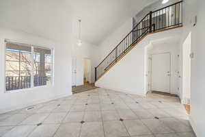 Entrance foyer with light tile patterned flooring, a towering ceiling, and a notable chandelier