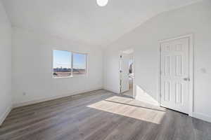 Empty room with lofted ceiling and hardwood / wood-style flooring