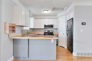 Kitchen featuring a breakfast bar, stainless steel appliances, kitchen peninsula, and white cabinets