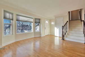 Foyer entrance with crown molding and light hardwood / wood-style flooring