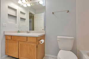 Bathroom featuring vanity, a tub to relax in, and toilet