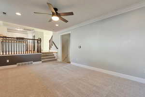 Unfurnished room featuring ceiling fan, light colored carpet, and ornamental molding