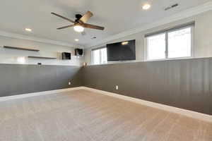 Carpeted spare room with crown molding and ceiling fan