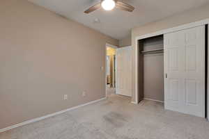 Unfurnished bedroom featuring light carpet, ceiling fan, and a closet