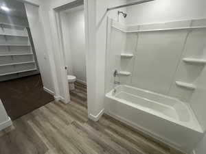 Bathroom featuring hardwood / wood-style flooring, toilet, and tub / shower combination