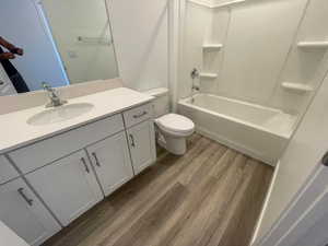 Full bathroom featuring vanity, hardwood / wood-style floors, shower / bathtub combination, and toilet