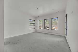 Spare room featuring concrete flooring and baseboards