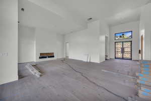 Unfurnished living room featuring a towering ceiling, wood finished floors, and baseboards