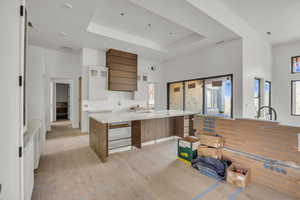 Kitchen with light wood-style floors, white cabinetry, a high ceiling, a tray ceiling, and glass insert cabinets