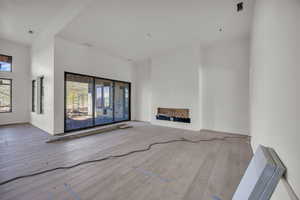 Unfurnished living room featuring hardwood / wood-style flooring and a towering ceiling
