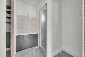 Full bathroom with a tile shower and baseboards