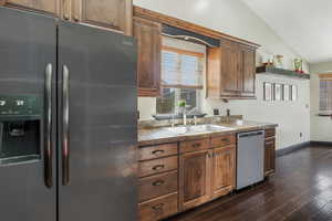 Kitchen with lofted ceiling, sink, dark hardwood / wood-style floors, and appliances with stainless steel finishes