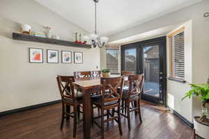 Dining room with lofted ceiling, dark hardwood / wood-style floors, and a chandelier