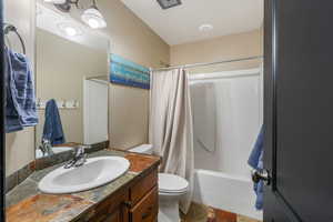 Full bathroom with toilet, vanity, and shower / bath combo with shower curtain