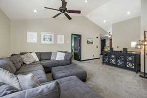 Living room with light carpet, high vaulted ceiling, and ceiling fan