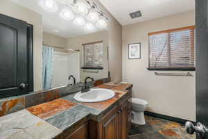 Bathroom featuring vanity, toilet, and curtained shower