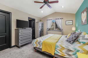 Carpeted bedroom featuring lofted ceiling and ceiling fan